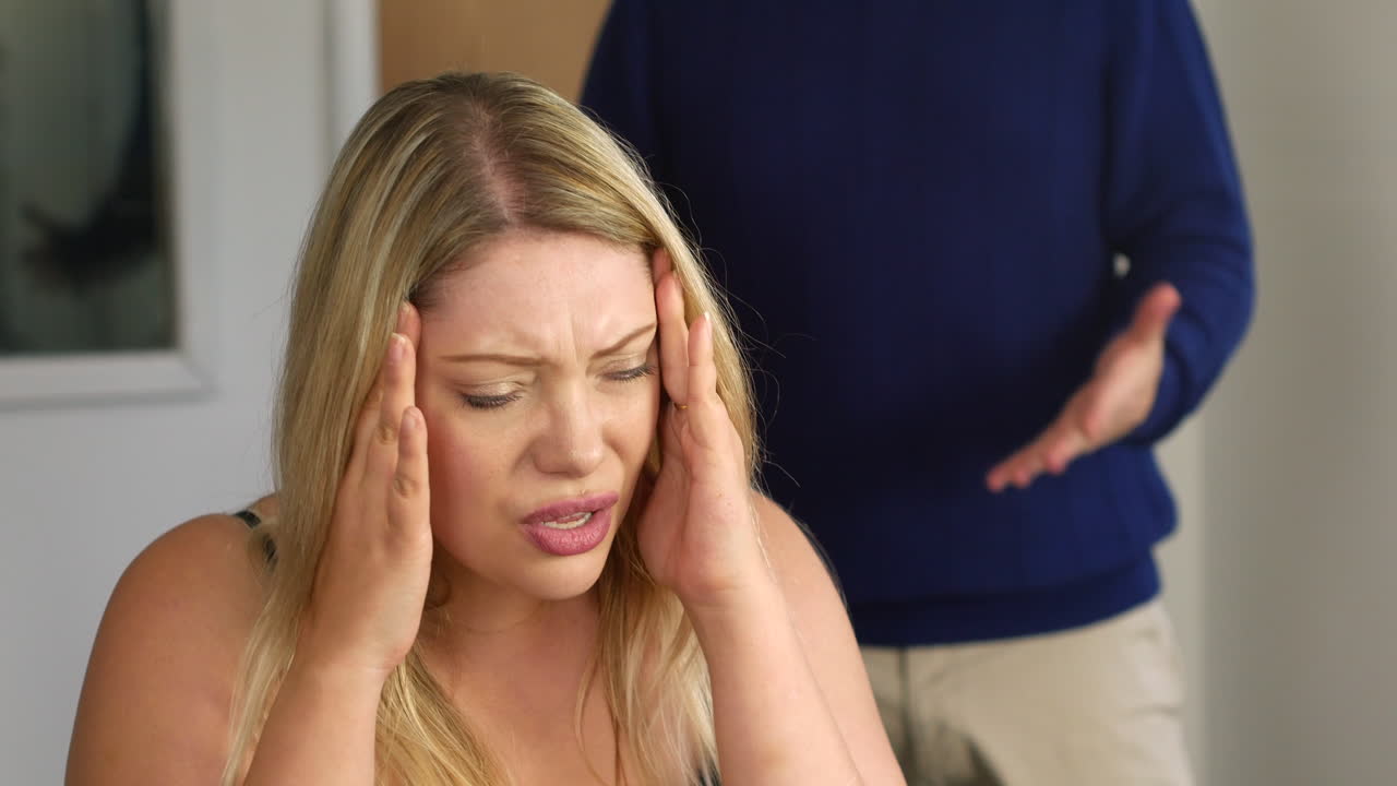 Attractive young couple arguing in home office. The blonde woman is upset and her boyfriend leaves in anger.