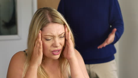 attractive young couple arguing in home office. the blonde woman is upset and her boyfriend leaves in anger.