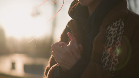 a close-up shot of a person rubbing their hands together thoughtfully, with the face not visible. the person is wearing a brown coat. the focus on the hands and the soft background blur