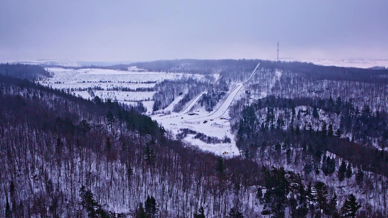 Droneopptak fra høy høyde av en elv som snor seg gjennom et vinterlandskap.