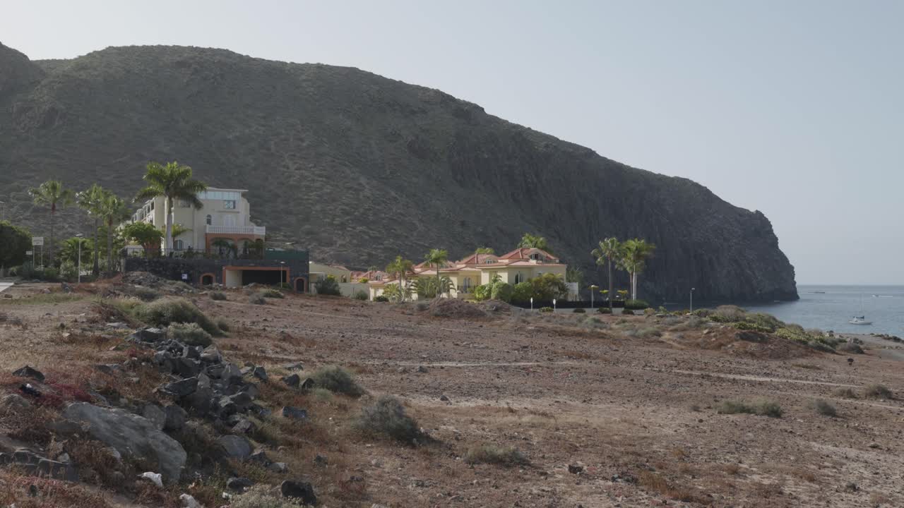 Buildings by the beach, cliffs and the ocean on a sunny day in Los Cristianos, Tenerife, Canary Islands, Spain.