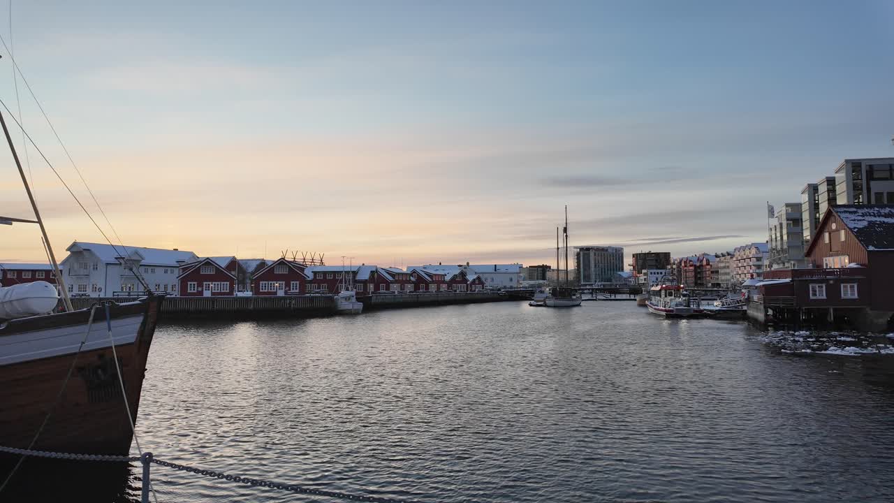A charming harbor at sunrise with red houses and boats, peaceful Svolvær winter view