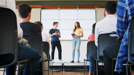 two students giving presentation to high school class in front of screen