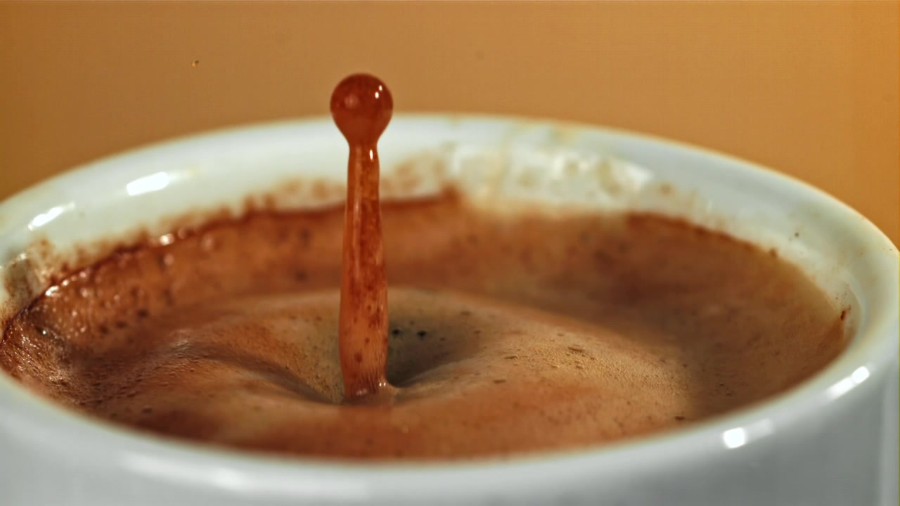 Goccia di caffè al rallentatore che schizza in una tazza bianca