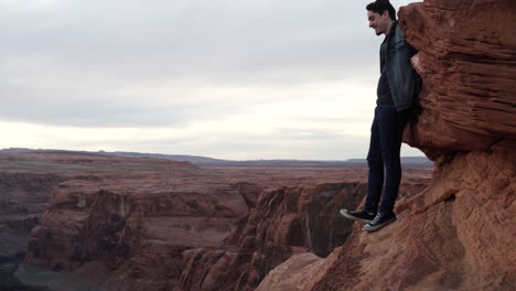 Daredevil-Man-Stands-on-the-Edge-of-River-Canyon-|-Horseshoe-Bend-during-Sunset-in-Page,-Arizona