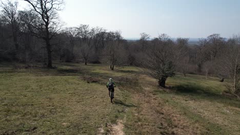 Drohne,-Die-Elektrisches-Mountainbike-Bergab-In-Epping-Forest,-Großbritannien,-Verfolgt