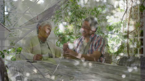 in garden, elderly couple drinking coffee and conversing with animation in sunlight