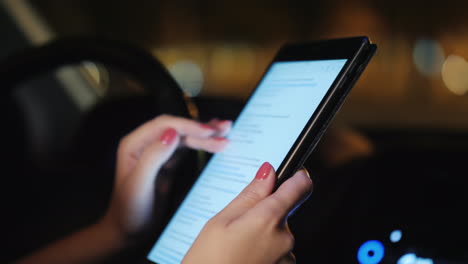 Eine-Frau-Benutzt-Ein-Tablet-Im-Auto-Abends-Ist-Der-Autoverkehr-Vor-Dem-Fenster-Sichtbar-Video
