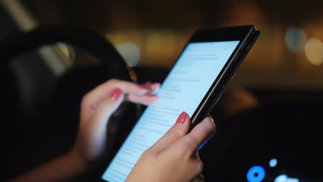 a woman uses a tablet inside the car evening the traffic of cars is visible outside the window video