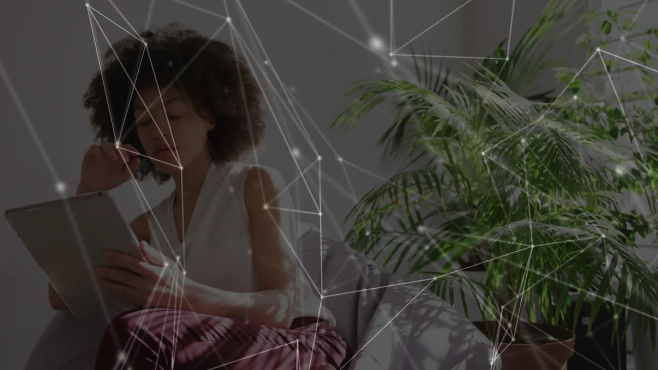 Donna che avvicina il tablet e lo tocca seduta su una sedia, nodi in movimento che si spostano e nascondono il palmo per la tecnologia.