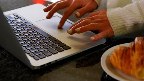 Woman-using-laptop-in-kitchen-at-home-4k