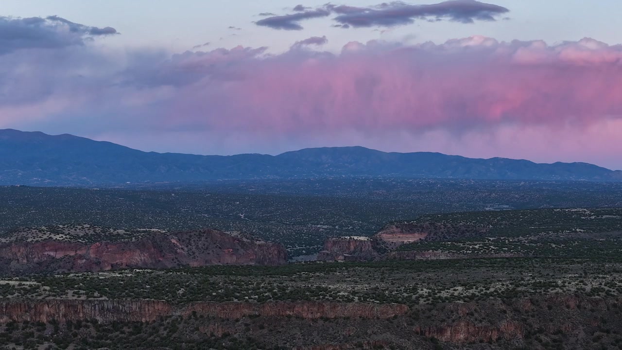 4K drone-timelapse indfanger solnedgangens sidste stråler, der skifter fra en bjergtop til mørke regnskyer. Filmatiske atmosfæriske bevægelser viser sydvestlig ørkengeografi og vejrskift.