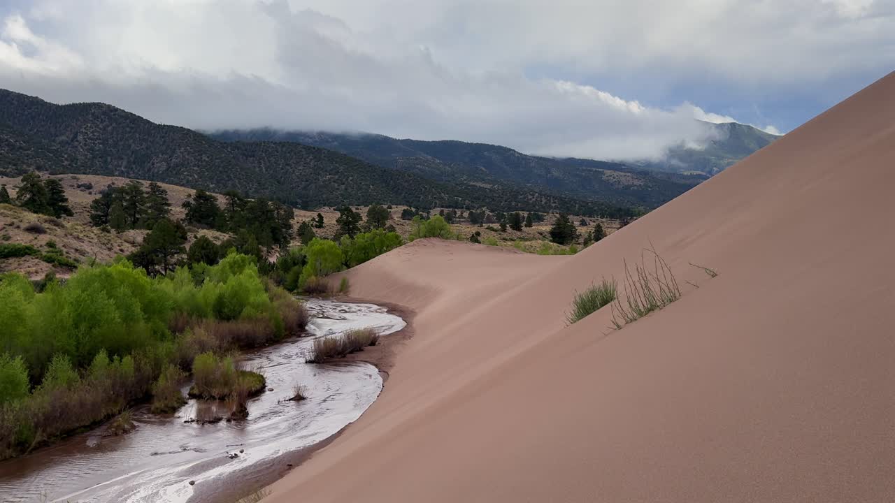 Medano Creek river landscape Great Sand Dunes National Park Sangre de Cristo range Rocky Mountains spring summer raining cloudy Colorado unique magical large amounts of sand dune hills windy