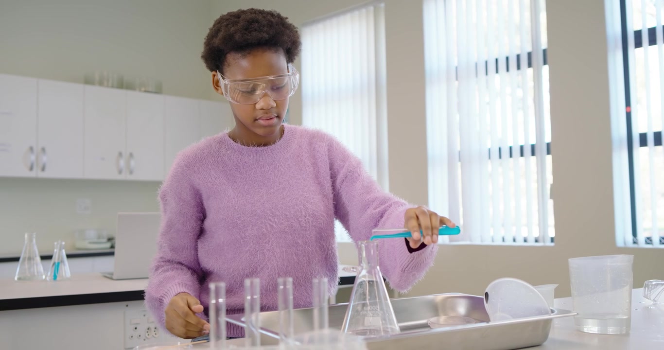 Teenage student picking pitcher pouring into flask adding blue tube mixing for class at lab bench