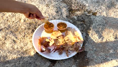 hand sampling grilled seafood on a plate