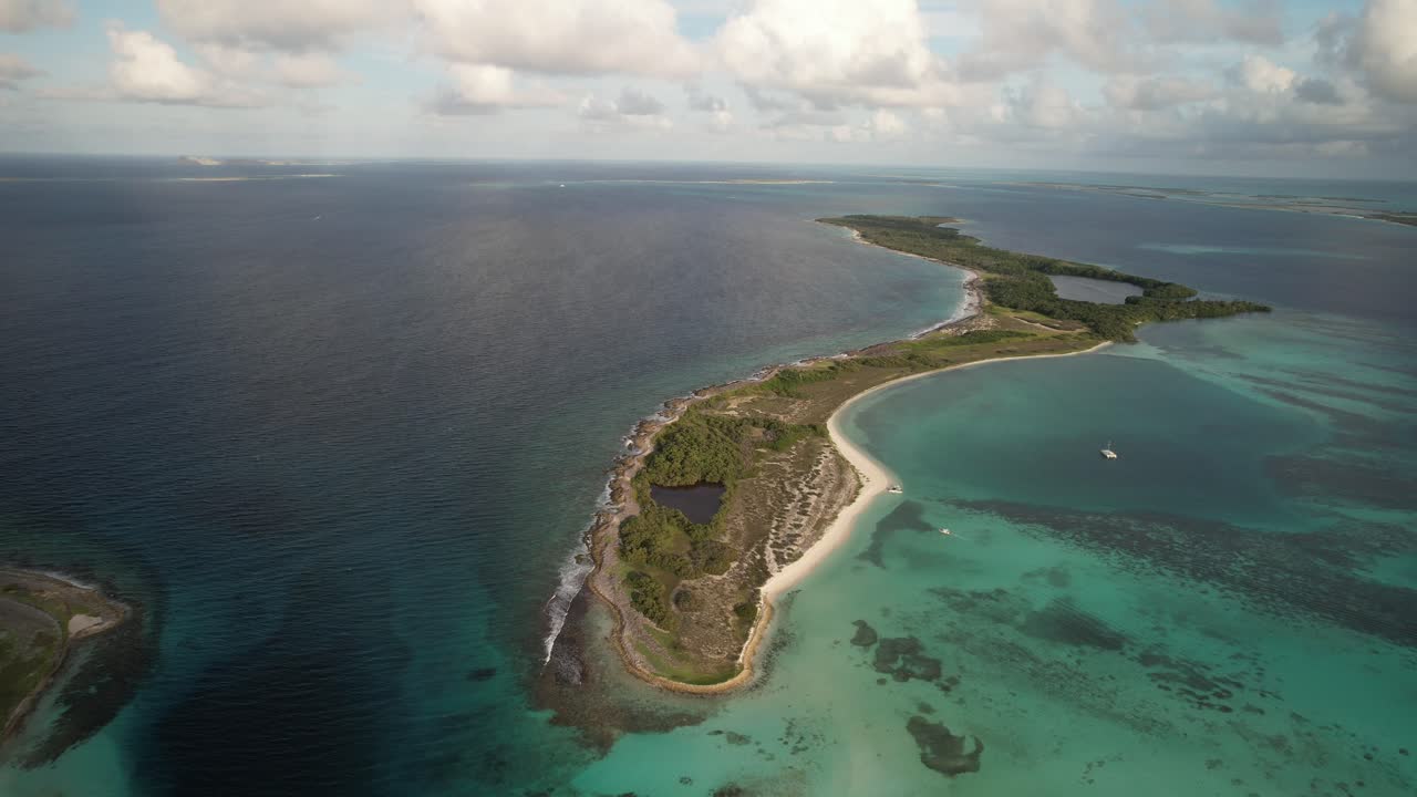 A scenic beach with turquoise waters, a smooth coastline, and lush greenery, aerial view