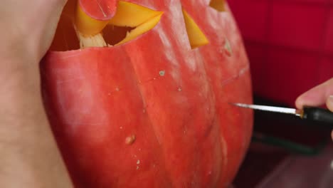 knife carving a creepy smile on big pumpking for halloween decoration, spooky jack-o-lantern decor close-up