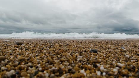 Slow-Motion-Waves-Breaking-on-Pebble-Cornish-Beach-with-Dark-Clouds