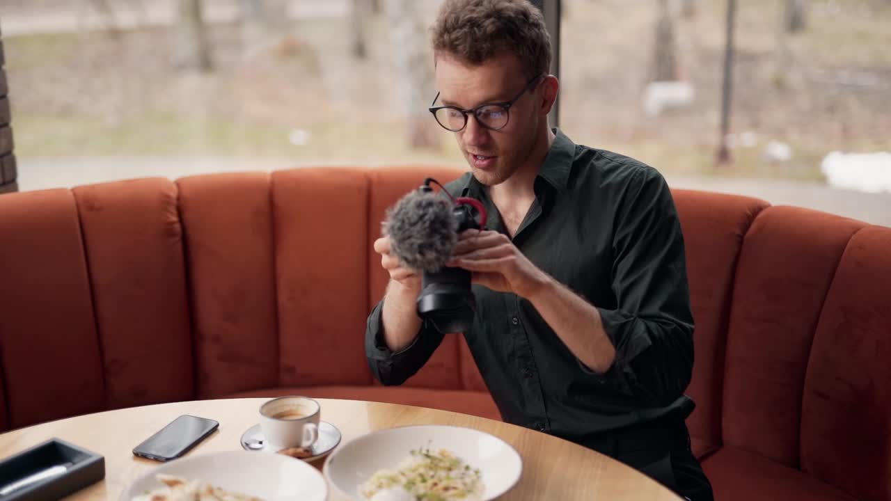 carismático fotógrafo de comida masculino dispara comida en una mesa en un restaurante junto a la ventana