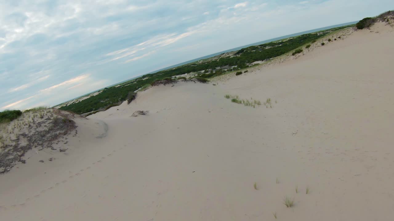 пролет над живописным ландшафтом с листвой, песчаными дюнами и тропами, ведущими к атлантическому океану на горизонте