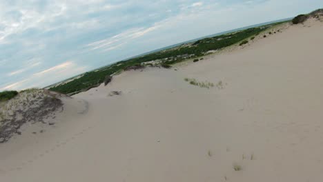 sobrevuelo aéreo del paisaje escénico con follaje, dunas de arena y senderos que conducen al océano atlántico en el horizonte