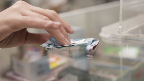 primer plano de manos dando pago con peso filipino en mostrador de vidrio en farmacia