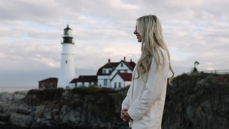 Schönes-Blondes-Modell-Lächelnd,-Leuchtturm-Im-Hintergrund