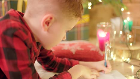 young boy is laying on the floor, writing his wish list for christmas