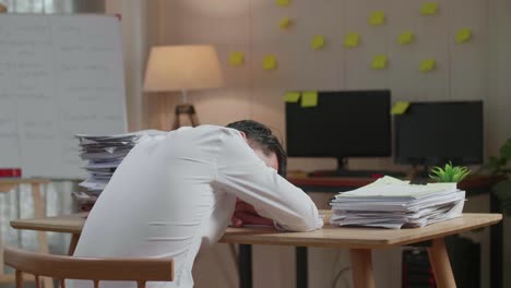 back view of asian man sleeping while working hard with documents at the office