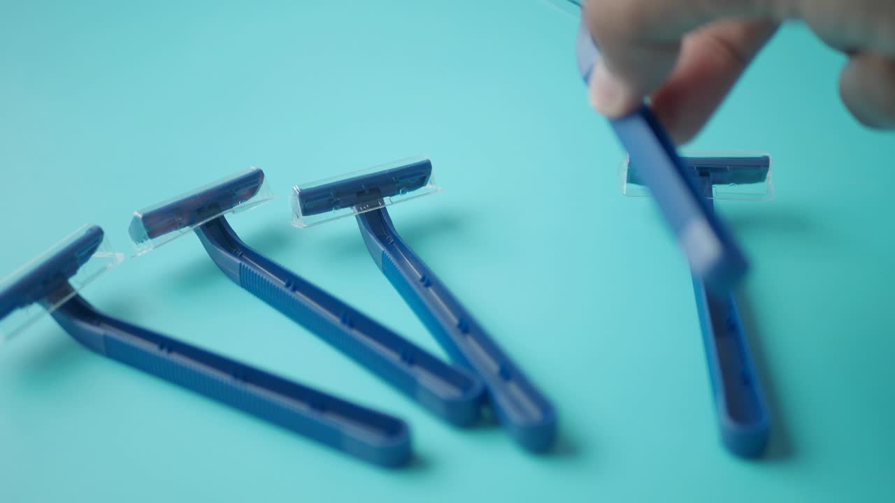 primer plano de una mano seleccionando máquinas de afeitar desechables azules