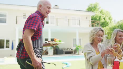 familia caucásica feliz teniendo barbacoa y comiendo en el jardín