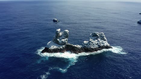 Roca-Partida-islet-in-Mexican-Pacific-surrounded-by-dive-boats,-aerial-arc