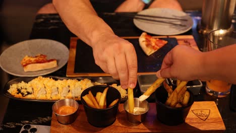 two people enjoying fries and dipping sauces