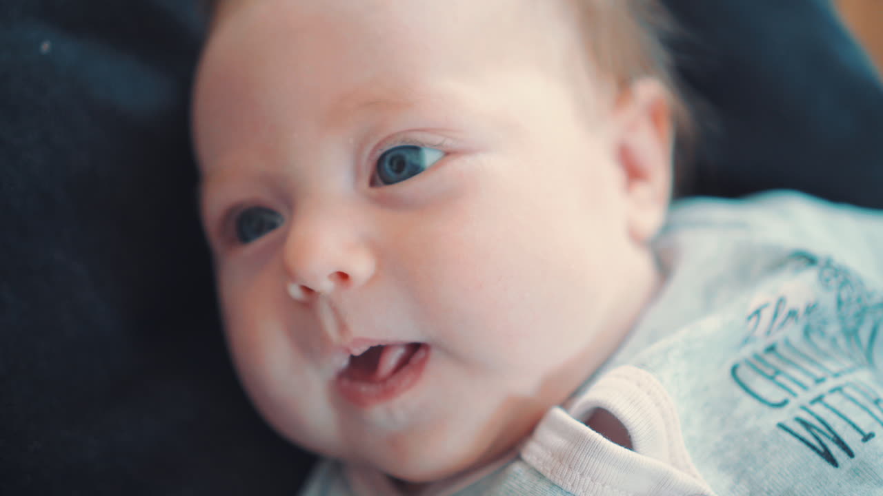 검은 배경에 누워 웃고 있는 아름다운 파란 눈의 신생아