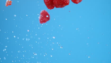 Eine-Gruppe-Von-Frischen-Himbeeren-Und-Wasser-In-Die-Luft-Geworfen,-Fliegen