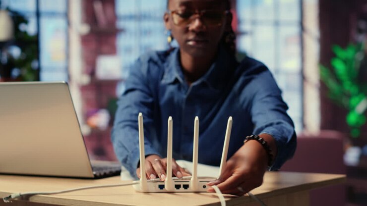 African american woman restarting her wireless router and checking network