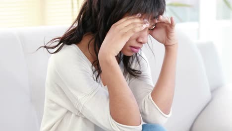 stressed woman holding her head on couch