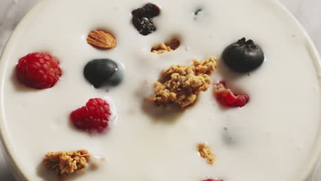 yogur de vainilla con granola y moras blancas en cuchara