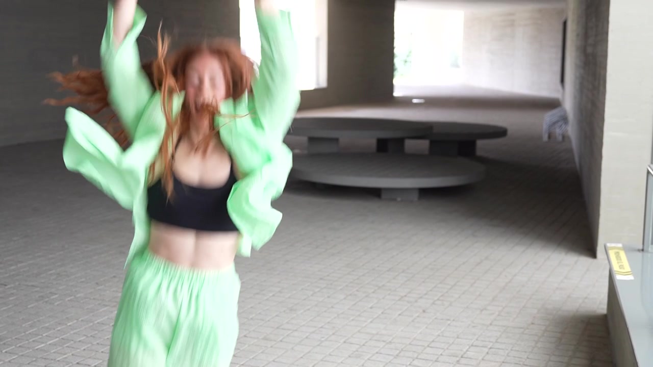 A joyful young woman happily dancing outdoors in a neon green outfit displaying confidence and joy