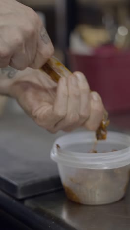 a person squeezing ingredients into a container during food preparation