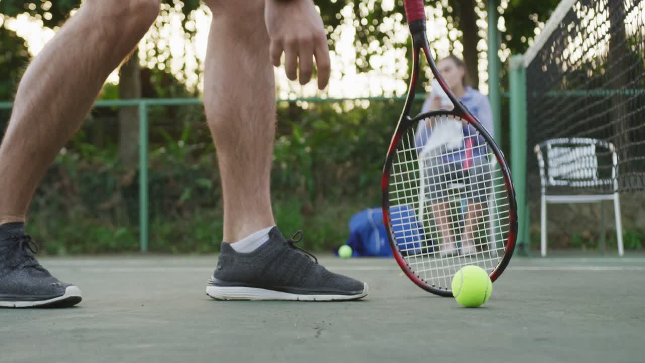 Video of happy caucasian men picking up ball on the court