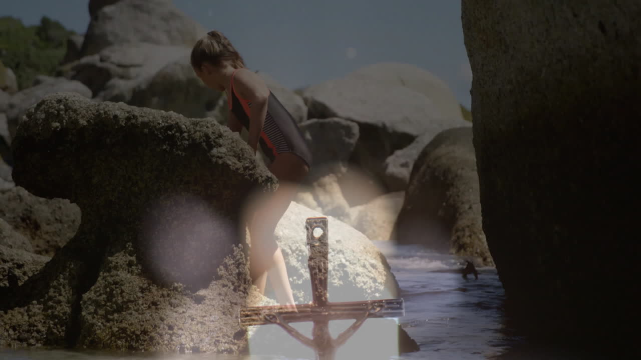 Climbing rocks at beach, child enjoying animation with abstract light overlay
