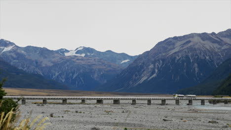 un gran camión que atraviesa un puente sobre un río en arthur's pass, nueva zelanda