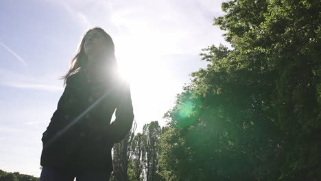 Portrait-of-a-fashionable-and-beautiful-Italian-model-walking-in-a-tranquil-park-wearing-a-black-coat-in-London,-United-Kingdom