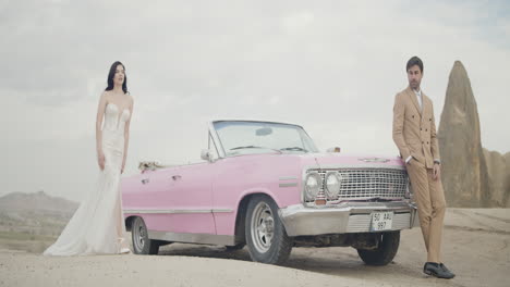 romantic wedding couple in a vintage pink car