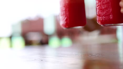 hands holding vibrant watermelon juice jars in a bright, airy phuket cafe. natural lighting enhances the refreshing atmosphere