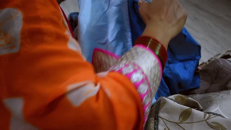 creando una mujer rasgando una vieja sábana azul para hacer cortinas para su casa.