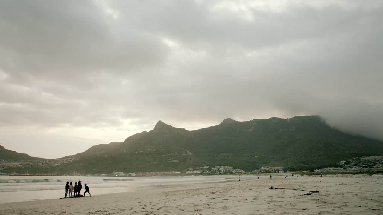 흐린 하늘과 흐릿한 산들을 배경으로 저녁에 남아공 하우트 베이에 있는 빈 해변의 잠긴 샷
