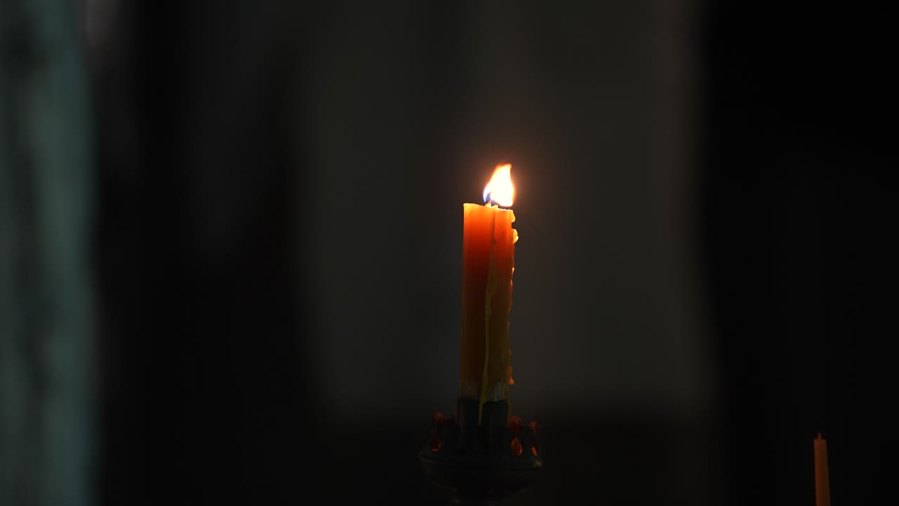 Izolovaný plamen hořící svíčky v temnotě jako symbol naděje
