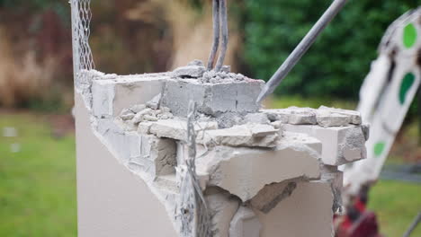 man makes house redevelopment, demolishes wall with a jackhammer, brick crumbles, plaster flies off in pieces, destruction of thick wall, hard work, major repairs, reconstruction - outdoors close-up